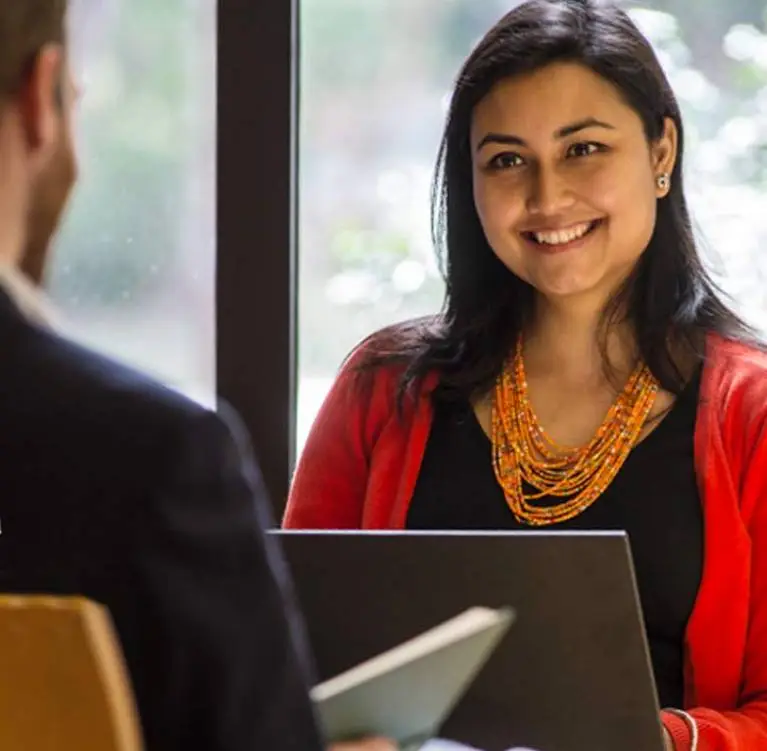 A woman sits across from a man at a desk.