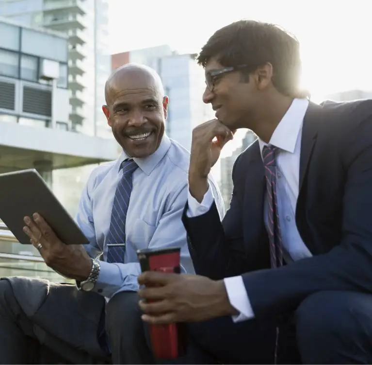 Two colleagues sit outside and look at a tablet
