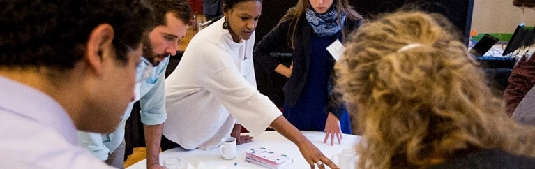 Students gather around a table to work on a project.